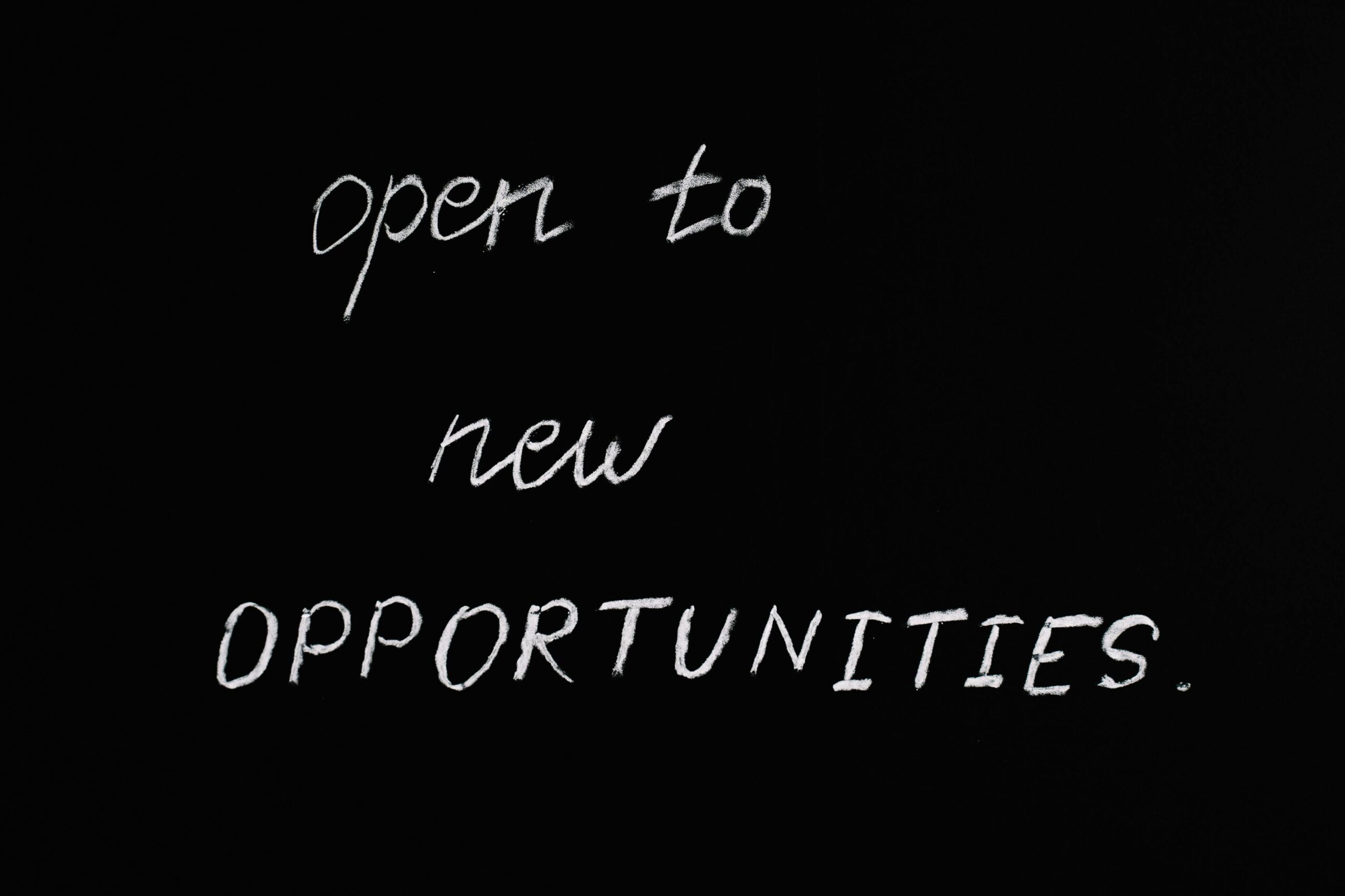 Blackboard with motivational quote 'Open to New Opportunities' in chalk writing.